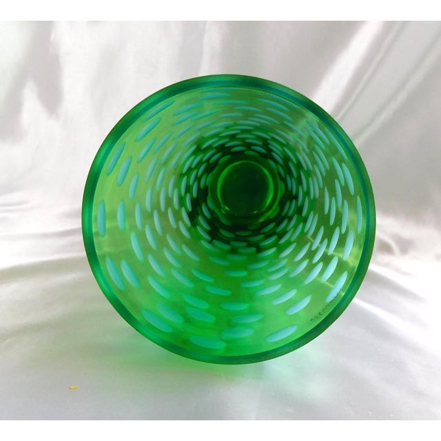 This is a very tall green Murano vase with cut to clear circles all around it. The base looks yellow and, according to...