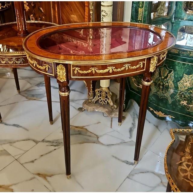 Showcase your treasured collectibles in timeless French elegance with this exquisite Louis XVI oval display side table....