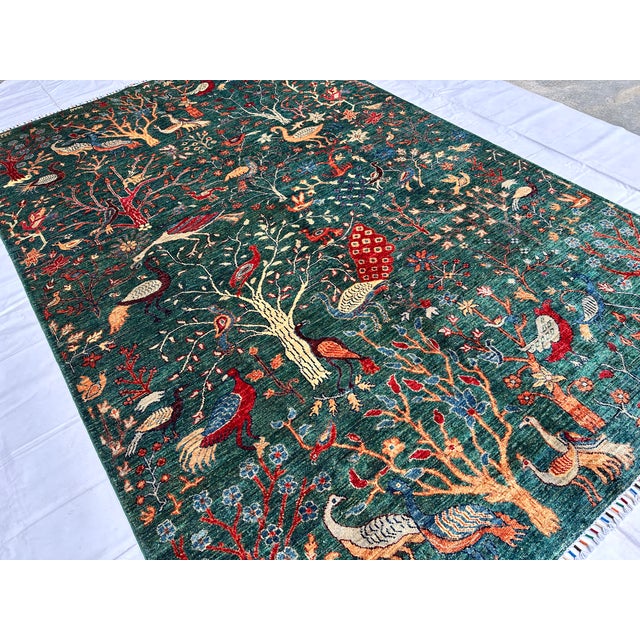 This hand-knotted Afghan pictorial rug is densely populated with peacocks, pheasants, and songbirds perched among...