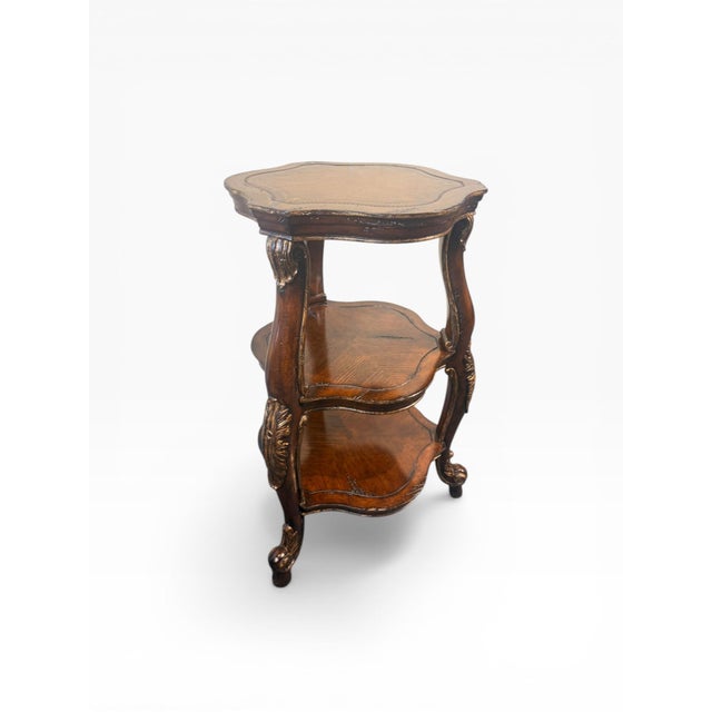 Charming vintage three-tier accent table featuring a scalloped form with carved details and subtle gilt accents...