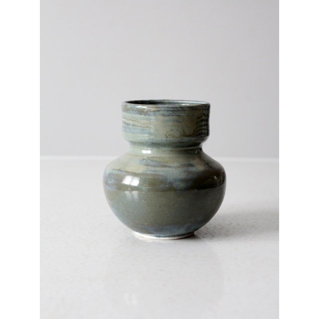 This vintage handmade studio pottery vase features a balanced, rounded form and a flowing glaze in soft grays, blues, and...