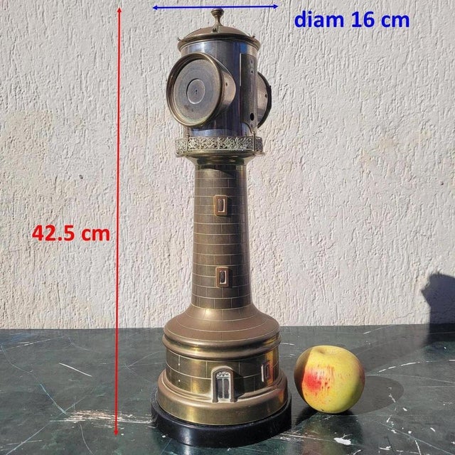 A patinated bronze clock depicting a lighthouse with architectural decoration: the shaft is adorned with windows and...