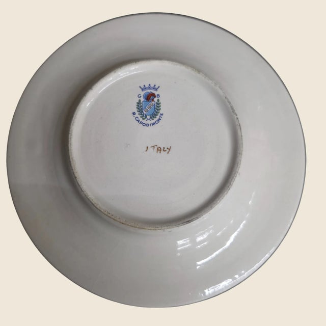 An elegant six-piece porcelain tea cup and saucer set, hand-painted in white with rich gold trim and jewel-tone burgundy,...