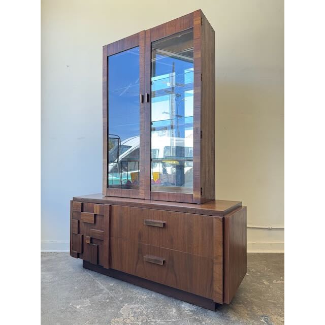 Striking Lane Brutalist display cabinet crafted in rich walnut, featuring bold geometric carved details, glass display...