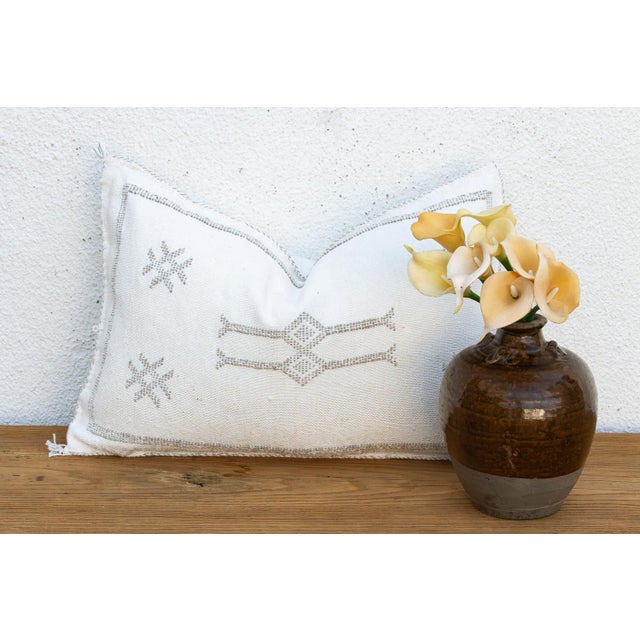 Four star motifs anchor the top of this handcrafted Moroccan cactus silk lumbar pillow, framing a stacked bowtie-diamond...