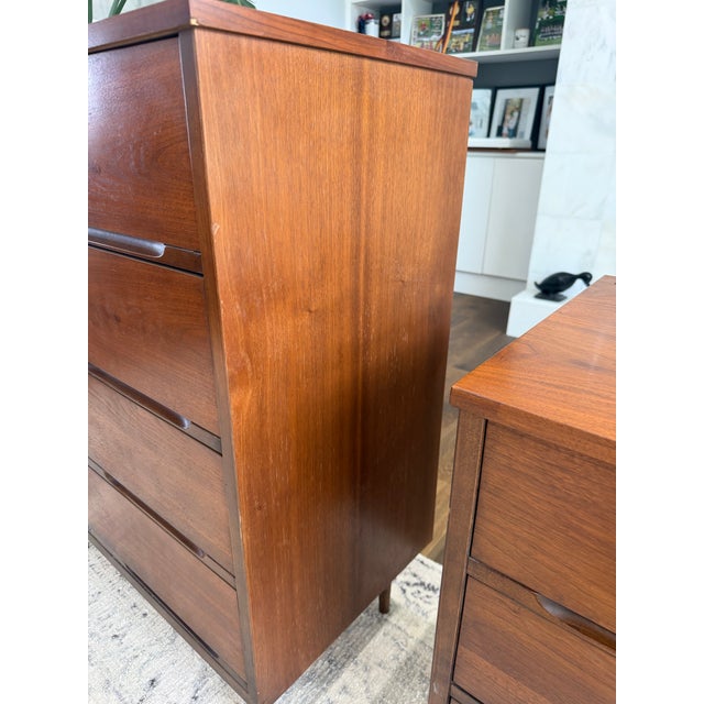Stunning mid century modern tallboy dresser featuring sleek lines, sculpted drawer pulls, and elegant tapered legs. A...