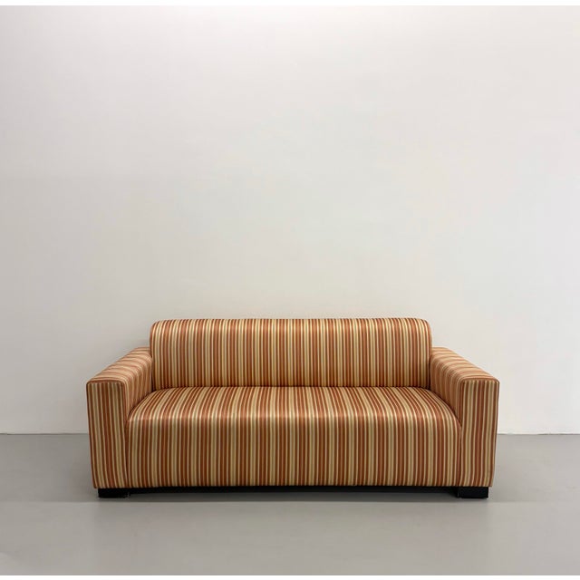 A clean-lined vintage postmodern sofa featuring a tailored silhouette with wide track arms and a fully upholstered frame....