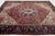 This Vintage Heriz wool rug has a red field, a purple-blue frame, and multicolor accents throughout the medallion motif....