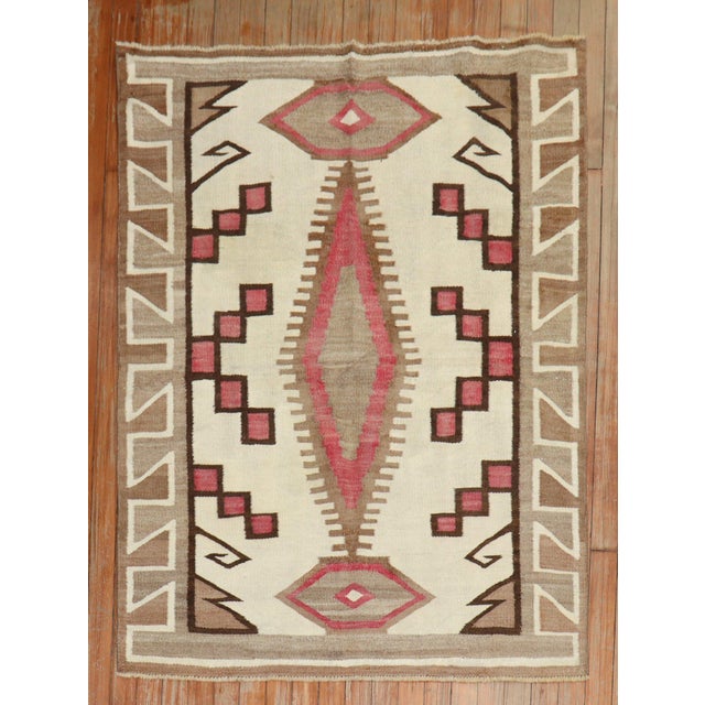 A highly decorative 20th-century American Navajo Rug with a geometric tribal design with pink, camel and brown accents on...