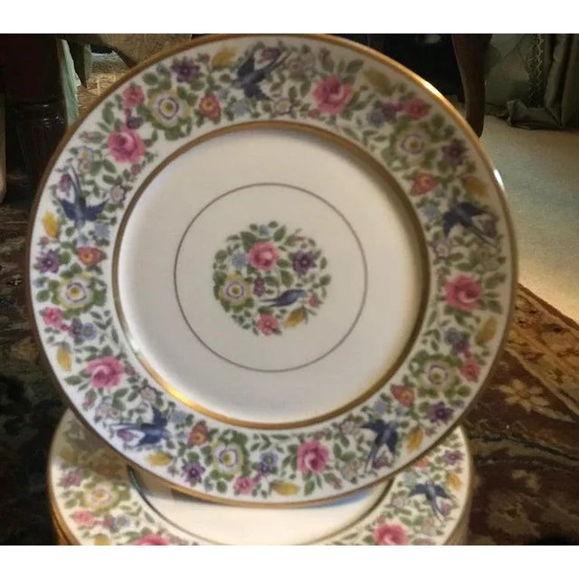 A set of nine floral service plates 10.25 inches in diameter, with gilt banding. The broad floral ban with birds and gold...