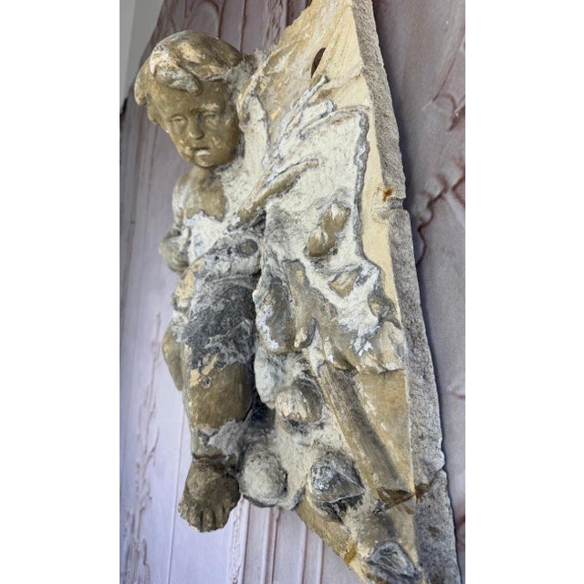 An extraordinarily evocative and rare antique French architectural fragment featuring a winged cherub, or putto, in high...
