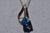 The Vidor: Signed Two Tone Pendant with Blue Topaz. The necklace features a central trillion cut Swiss blue topaz in the...