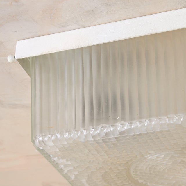 A refined study in mid-century French craftsmanship, this 1950s flush mount centers on a square Holophane glass shade  a...