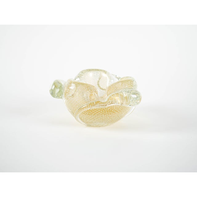 The ashtray was made in the 1960s in Italy. An impressive, hand-formed ashtray made of thick glass in shades of golden...