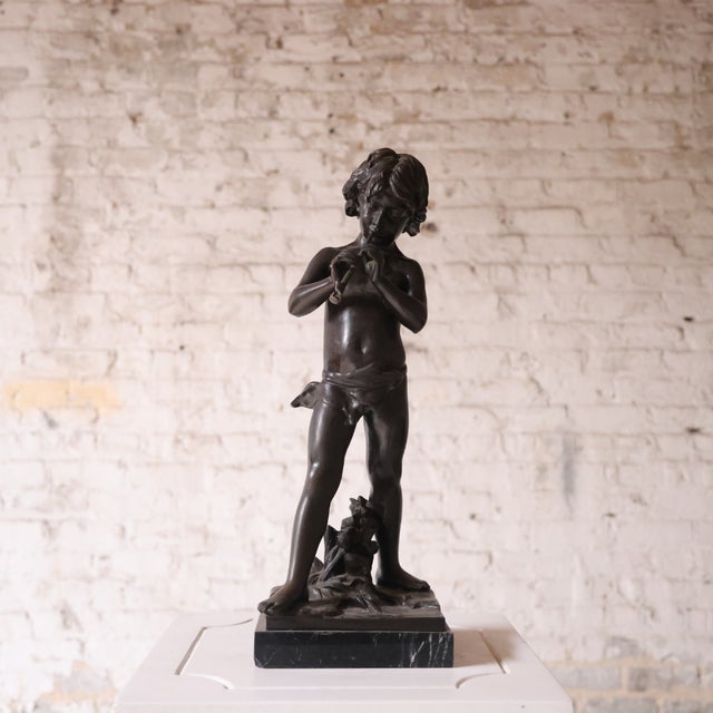 A finely cast 19th-century French bronze sculpture depicting a young boy standing in a relaxed, naturalistic pose. The...