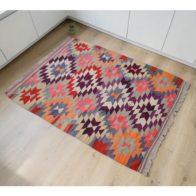 This authentic 1950s Mediterranean Anatolian kilim features a vibrant geometric design in deep plum, orange, and cream,...