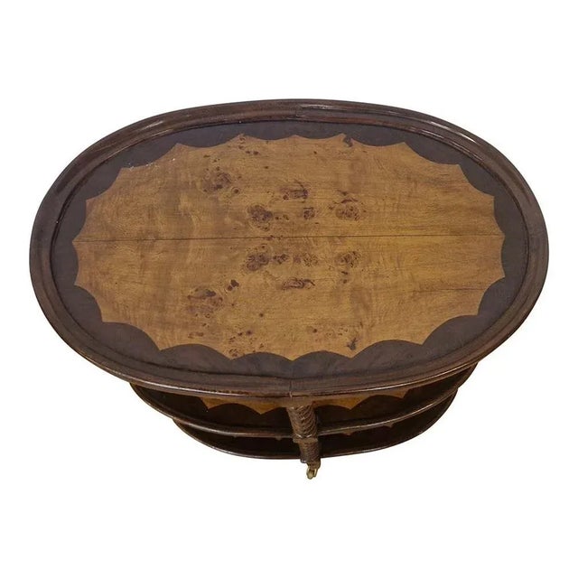 Oval coffee table with wheels on four turned legs, in walnut and briar, two intermediate shelves. Dimensions (WxDxH) 60.5...