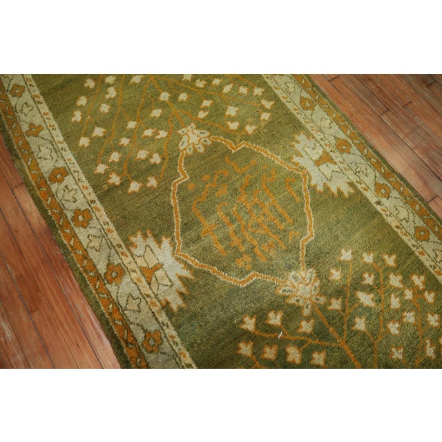 An early 20th century antique Oushak runner in forest green, gold and ivory Measures: 3'10'' x 11'10''.