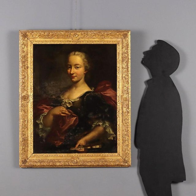 Oil on canvas. The noblewoman is richly attired in a dark velvet evening gown with white ruffles, pearl inserts, and a red...