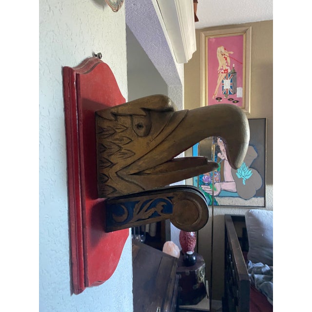 Gold, black and red painted carved wooden eagles head mounted on a red backing probably 1940s or 1960s