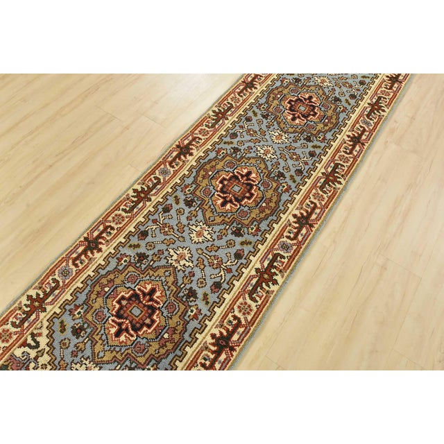 A traditional tribal Heriz runner hand-knotted with an all-wool pile on a cotton foundation. This oriental rug features...