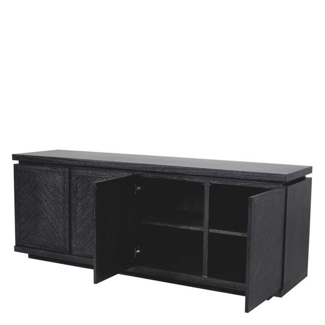 Contemporary sideboard in charcoal grey oak veneer. Its front features four handle-less doors, each with a herringbone...
