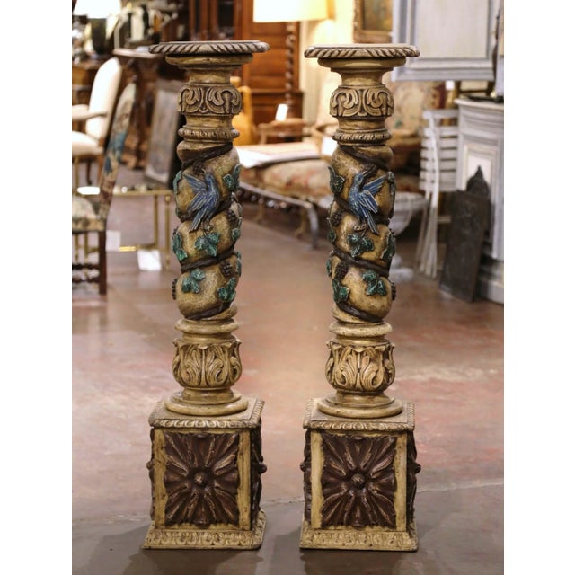 An exceptional pair of antique French carved and painted pedestals, richly decorated with grapevines, foliage, fruit...