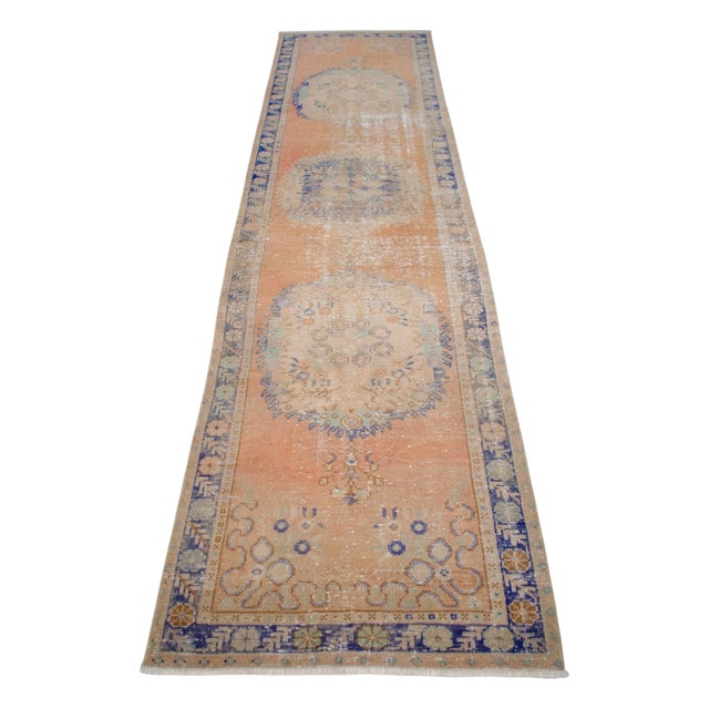 Vintage 1960s distressed Turkish Oushak rug runner. With wavy desaturated red-orange field and shades of blue, tan and...