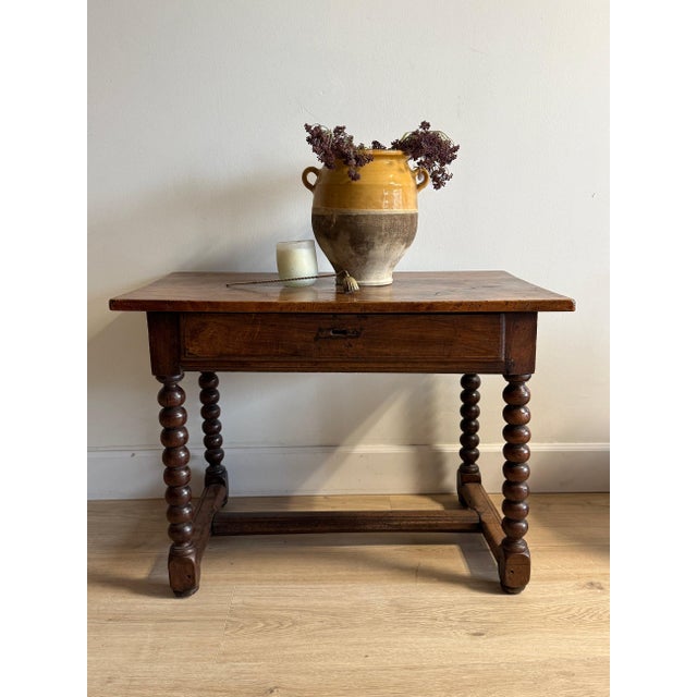 An 18th-century French walnut bobbin table, rich with the kind of patina only centuries of use can produce. The softly...