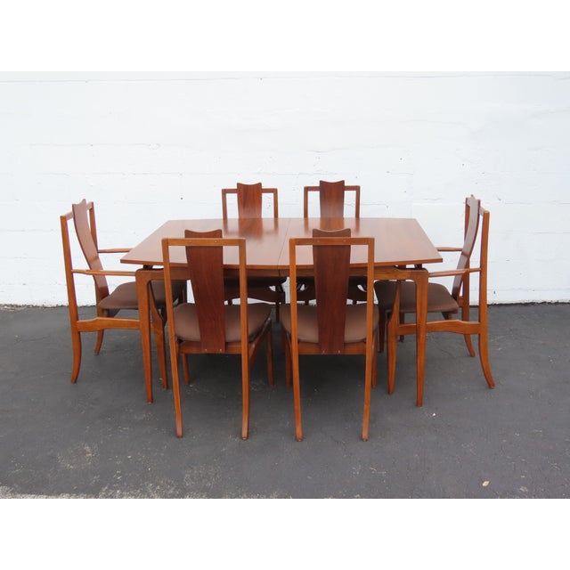 This Set of Dining Table and Six Chairs is made of wood, walnut, veneer, and upholstery. We believe it was made by Young...