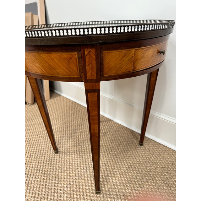 Beautiful marquetry on table and legs with white marble top. There are two drawers and two pullouts. Graceful legs end in...