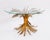 A striking Hollywood Regency coffee table with a gilded tole metal “Sheaf of Wheat” sculptural base and a glass top,...