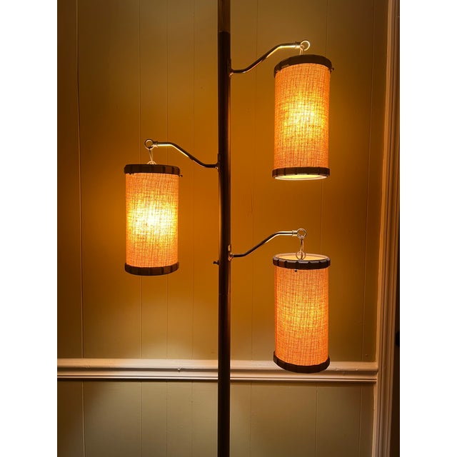 Gorgeous 1960s tension pole lamp with 3 lantern-style shades trimmed in lovely walnut detail. The warm, amber glow can...