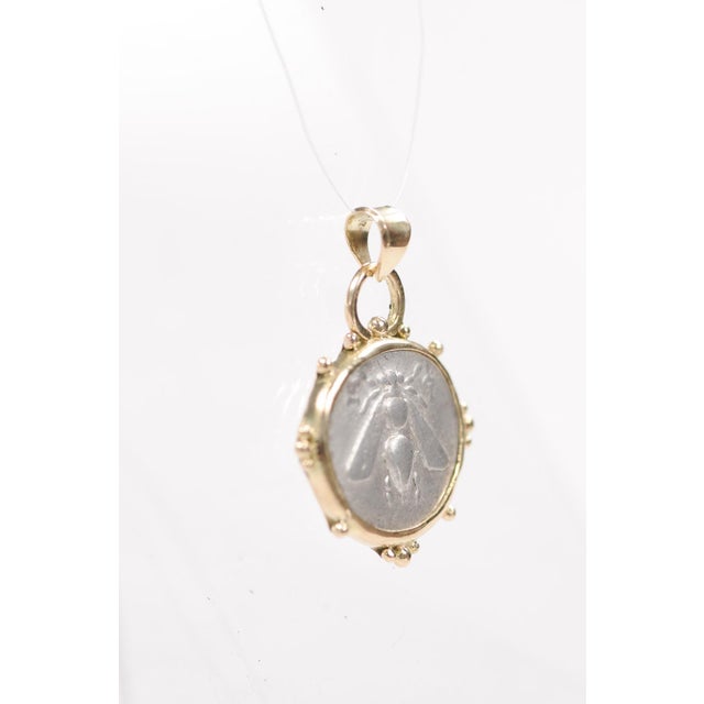 A Greek AR Drachm coin (4.13 grams) pendant of a bee set with 18 karat gold trim. This ancient coin was minted in Ionia,...