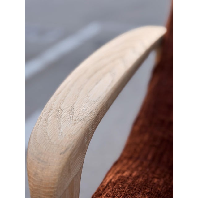 A beautifully restored lounge chair featuring an elegant sculptural solid oak frame paired with rich cinnamon chenille...