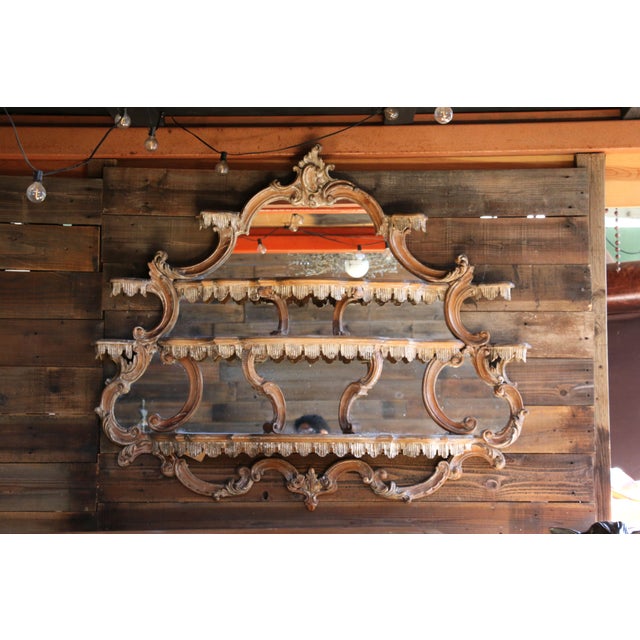 A beautifully ornate French Rococo Revival wall étagère, exquisitely crafted from carved wood and featuring a mirrored...