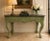 Hand-carved decorative console table featuring an olive green painted finish with exceptional relief carving throughout....