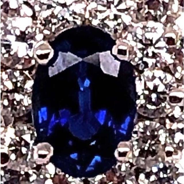 18 Karat White Gold Sapphire and Diamond Cluster Earrings. Pair of sapphires cluster earrings, the central oval faceted...