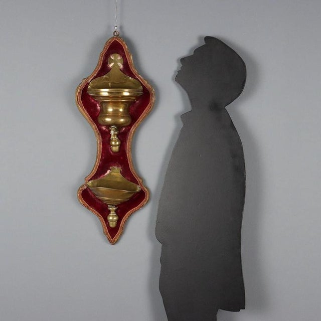 Brass fountain mounted on a shaped wooden panel covered in purple velvet. This piece is attributed to the mentioned...