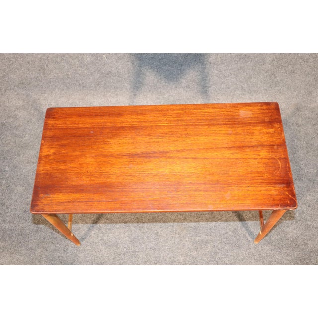 Mid-Century Modern Danish table in teak wood. Slender legs and wood runners with warm teak top. Please confirm location.