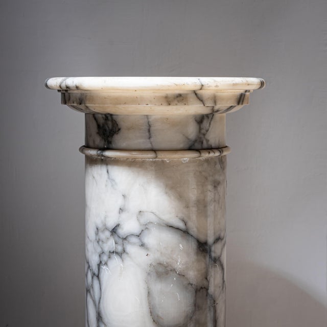 Column made of white marble with grey veining. The smooth shaft is divided by three subtle ring moldings. Resting on an...