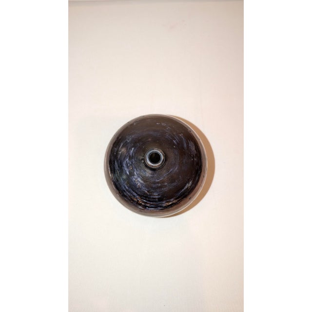 Bud vase by “Vivica and Otto.” Dark copper finish. Flat onion shape typical for their work. Dimensions: 3.25 X 4 inches.