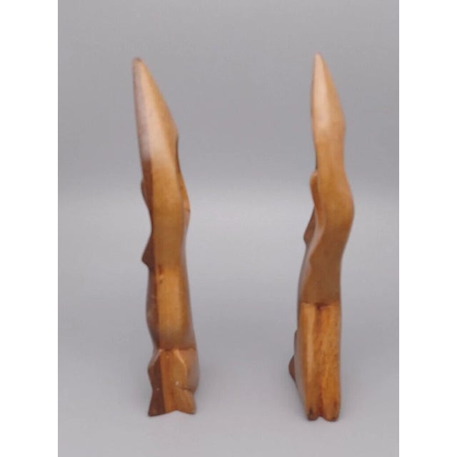 Striking vintage pair of hand-carved wooden abstract sculptures depicting kneeling women. These pieces feature smooth,...