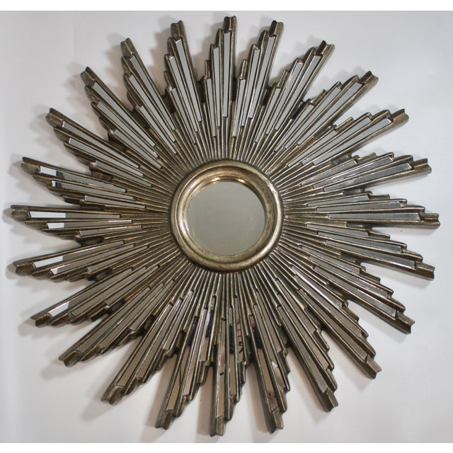 A stunning mid-century modern sunburst mirror composed of resin, circa 1960s. This is a lovely mirror with many mirrored...