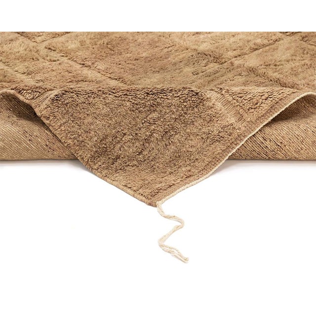 Warm earth tones trace a quiet grid across this handwoven wool rug, where subtle linear striations create depth without...