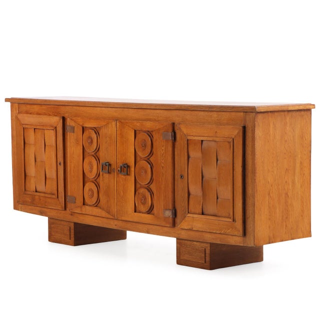 An impressive and substantial solid oak enfilade or sideboard executed in the monumental French mid-century regionalist...