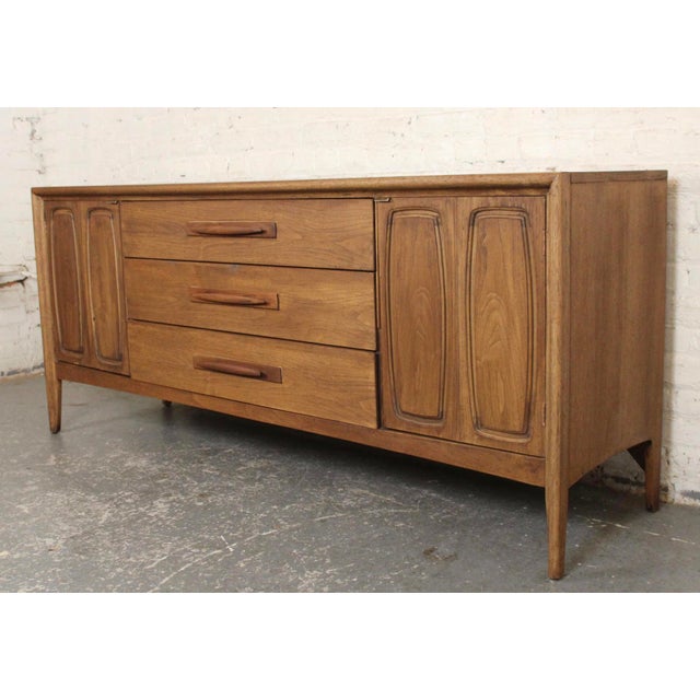 Long walnut dresser by Broyhill for their Emphasis line. Featuring nine total drawers. Two banks are concealed behind...
