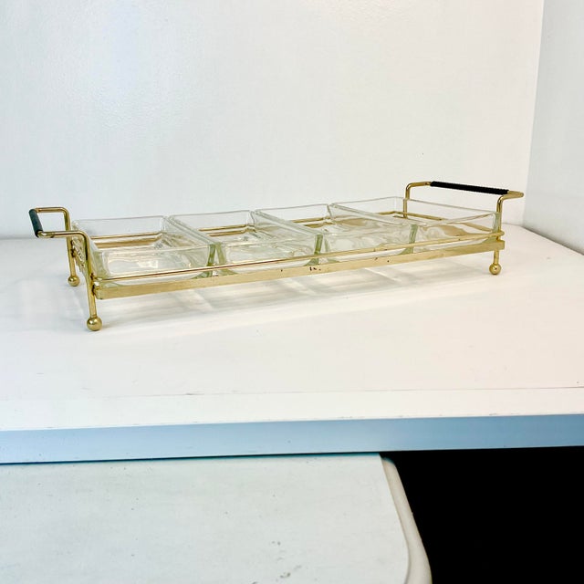 Offering a Mid-Century Atomic Relish Server. The piece has four individual glass dishes nestled in a gold colored Atomic...