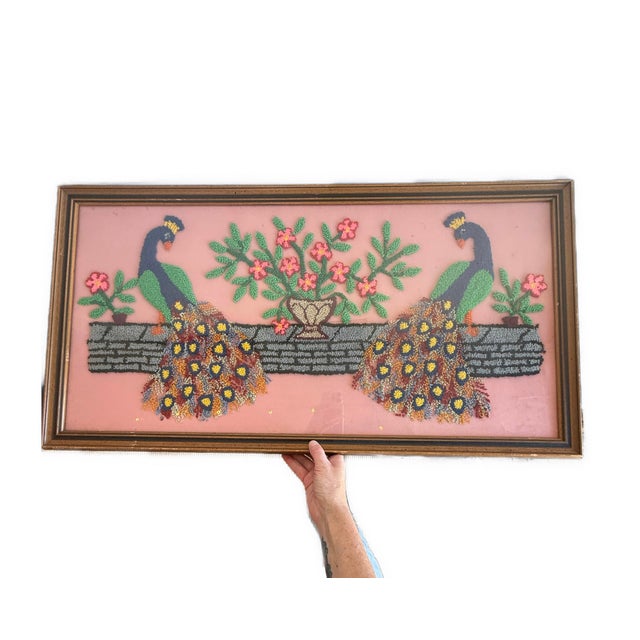 A pair of vibrant peacocks still on a grey stone wall in a garden; with pink flowers in this sizable hand-embroidered or...