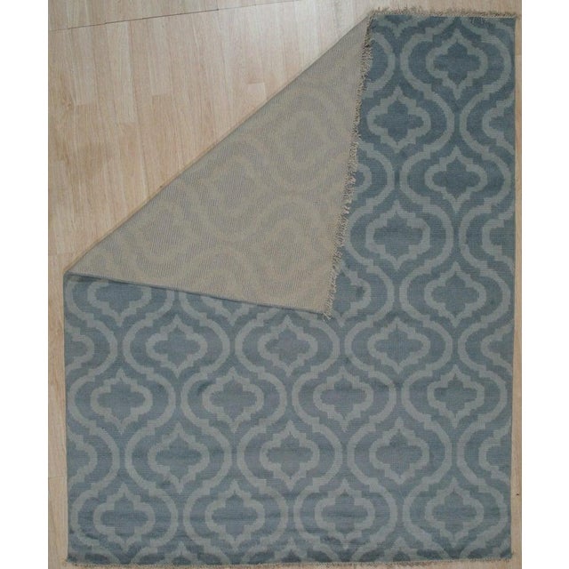 This blue wool rug is a hand knotted pile rug featuring a distinct Rabat style. Produced in India, this floor covering...